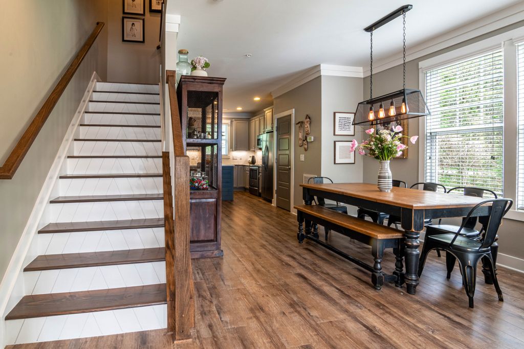 Bright and inviting dining area features a wooden table, staircase, and stylish interior lighting.