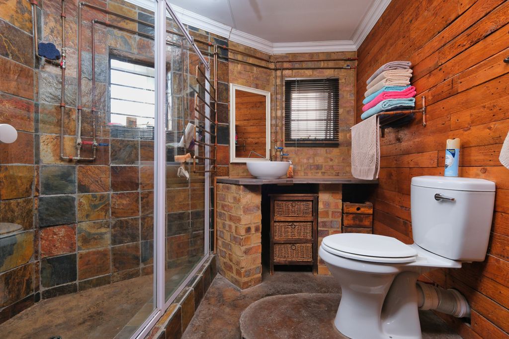 Charming rustic bathroom featuring brick walls, wood paneling, and modern amenities.
