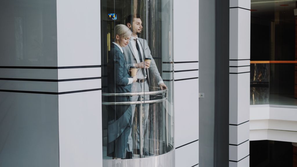 What Is a Shaftless Home Elevator? A Practical Guide for Homeowners Two business professionals in suits standing inside a modern glass elevator.