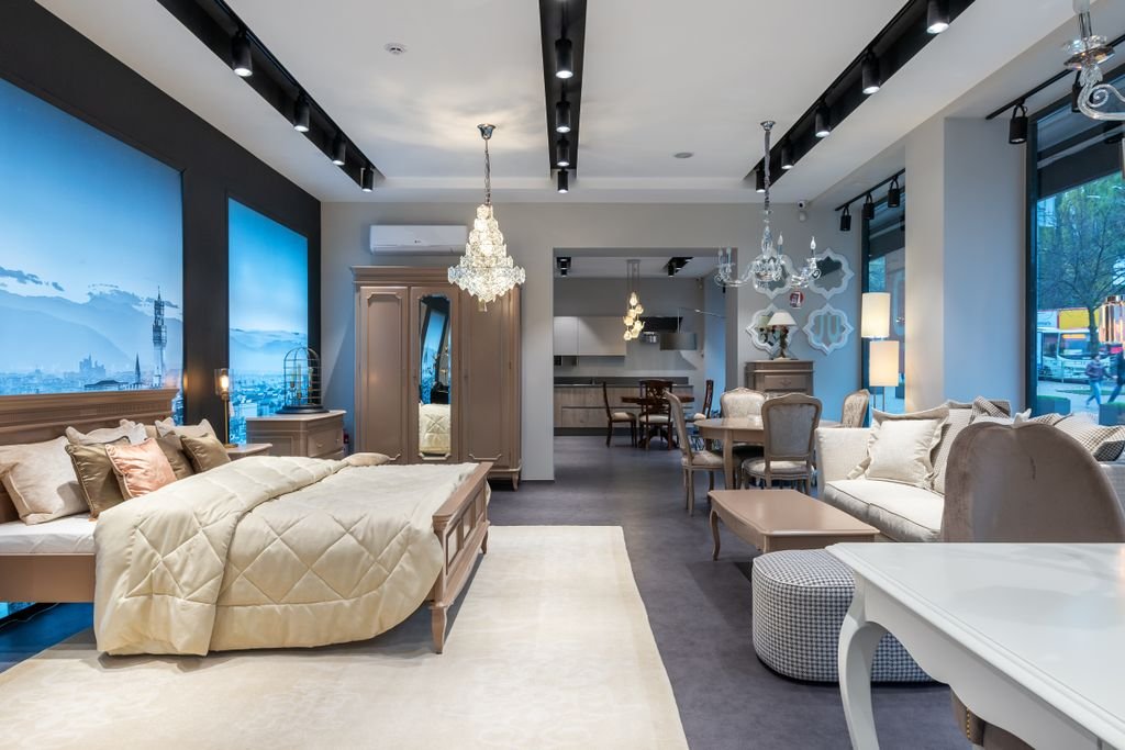 Bedroom Furniture Arrangement Ideas: 10 Smart Layouts Comfortable bed with chest of drawers and closet placed in front of elegant sofa and dining table in spacious contemporary furniture store with glowing lamps and monitors