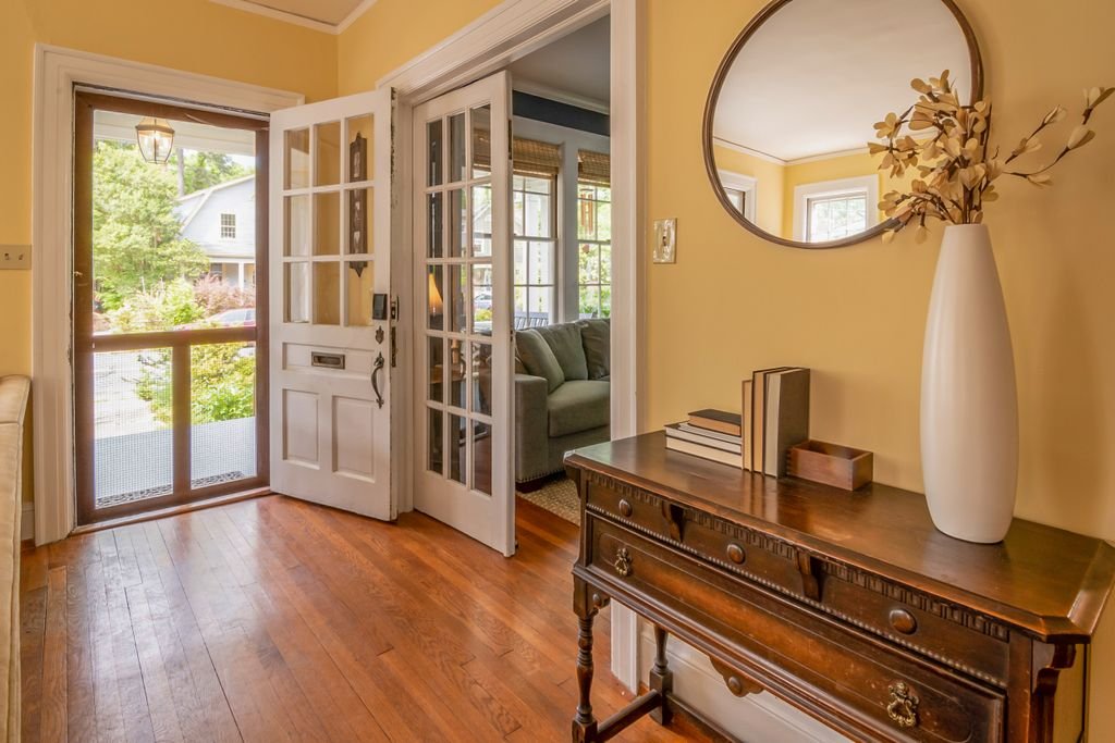 52 Foyer Ideas to Create a Stylish, Welcoming Entryway Sunlit entryway featuring a wooden dresser, mirror, and vase with decorative branches.